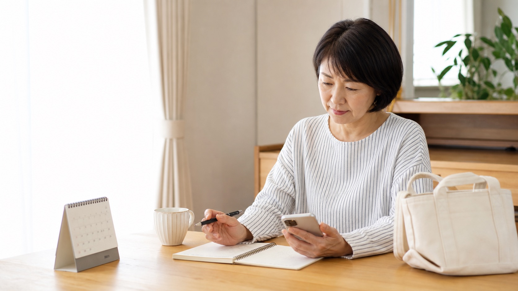 自宅の食卓でスマホとノートを見ながら短時間の仕事の条件を確認する60代前後の女性